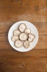 Teller mit Shiitake-Pilzen Lentinula edodes von oben auf Holztisch. — Stockfoto