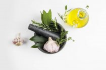 Mortar and pestle with garlic and herbs and olive oil. — Stock Photo