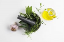 Mortaio e pestello con aglio ed erbe aromatiche e olio d'oliva . — Foto stock