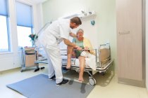 Госпиталь Гериатрии. Медсестра помогает запутавшемуся пациенту в старом отделении больницы. — стоковое фото