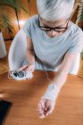 Senior woman doing wrist joint physical therapy with conductive TENS (transcutaneous electrical nerve stimulation) electrode cuff. — Stock Photo