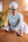 Mulher idosa fazendo fisioterapia com cotovelo TENS (estimulação elétrica nervosa transcutânea) almofadas de cinta de eletrodo . — Fotografia de Stock
