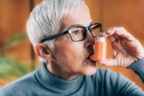 Seniorin inhaliert Medikamente aus Asthmapumpe. — Stockfoto
