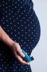 Image recadrée d'une femme enceinte tenant un appareil respiratoire pour l'asthme — Photo de stock