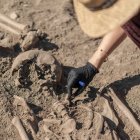 Arqueólogo excavando restos humanos antiguos en un sitio arqueológico. - foto de stock