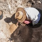Archaeologist digging with hand trowel, recovering pottery from an archaeological site. - foto de stock