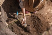 Arqueólogo excavando cerámica en un sitio arqueológico. - foto de stock