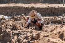 Escavações arqueológicas. Jovem arqueólogo escavando parte do esqueleto humano e crânio do chão. — Fotografia de Stock