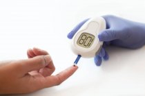 Doctor using a glucometer to take a blood glucose reading from a patient. — Stock Photo