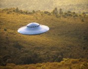 Illustration of a UFO gravitating over a forest and mountain ranges. — Stock Photo