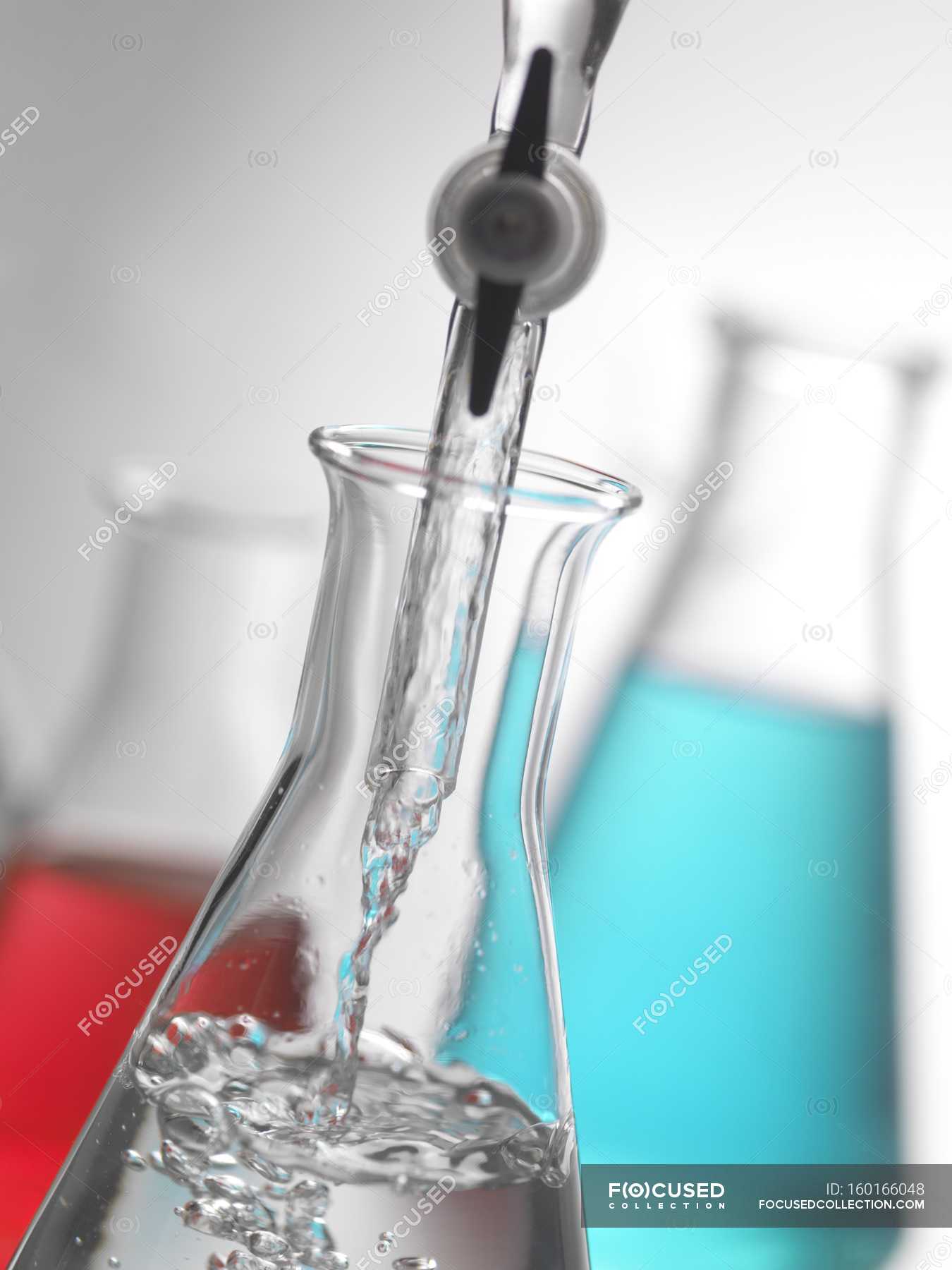 Fluid pouring into laboratory glassware. — still life, equipment