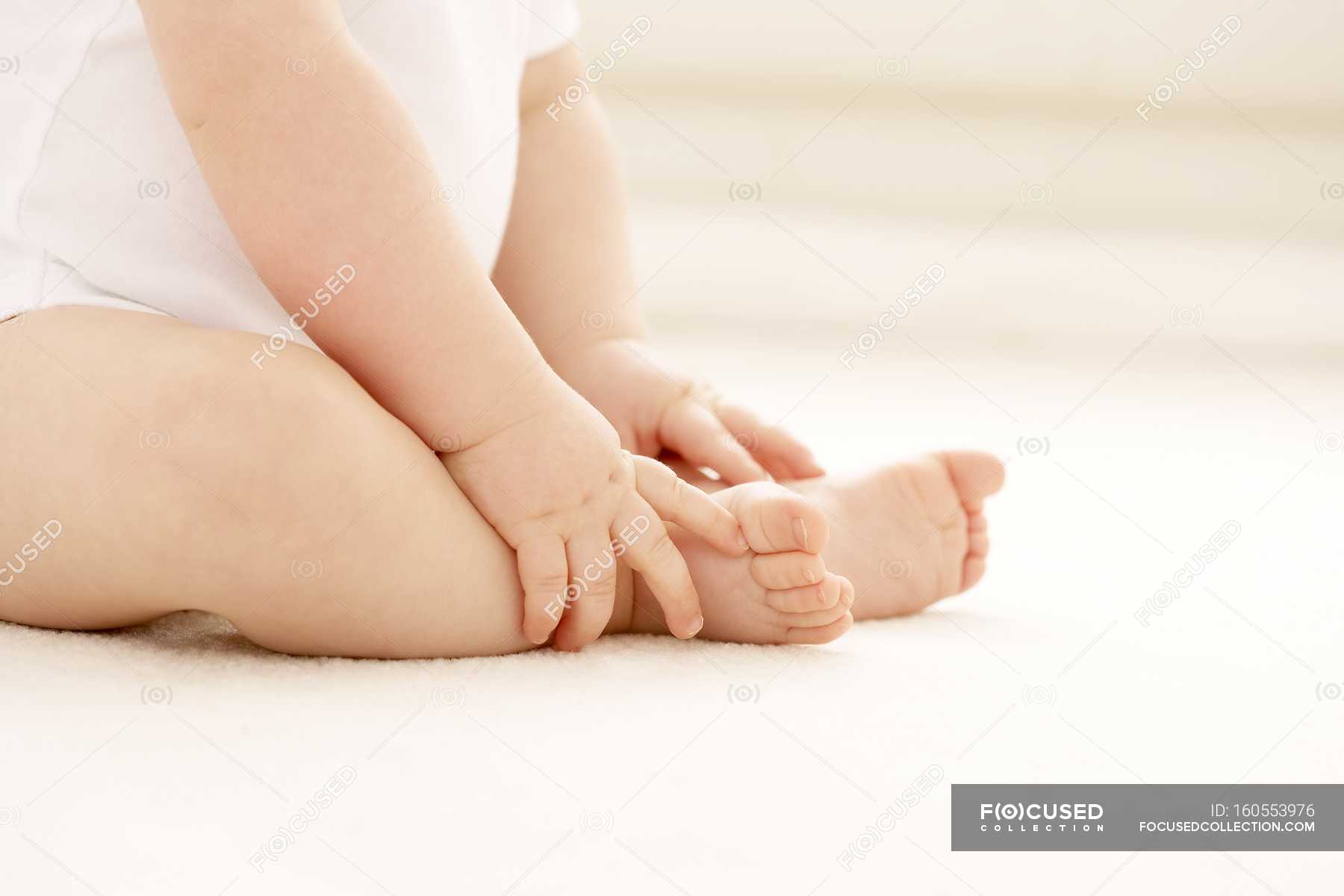 baby-holding-feet-while-sitting-on-floor-fingers-skin-stock-photo