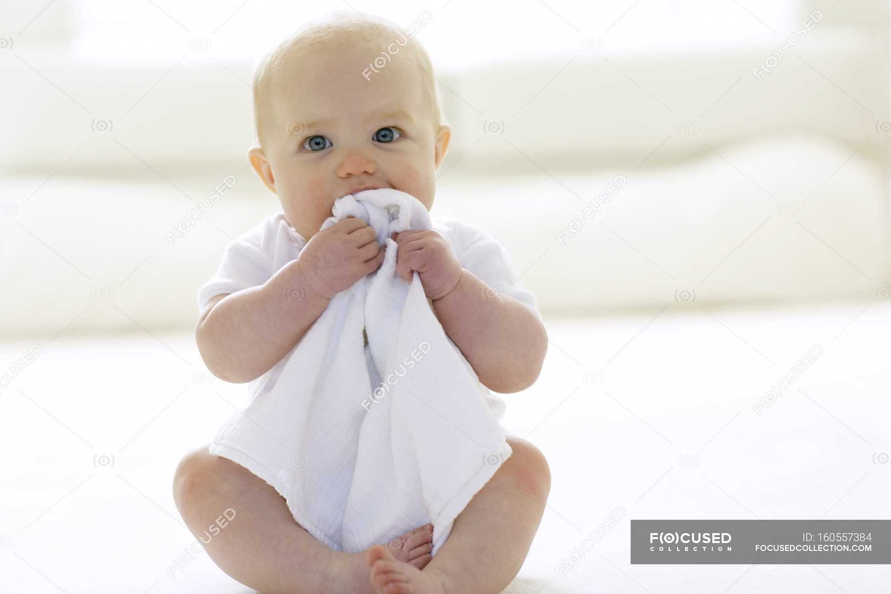 Baby girl chewing blanket on floor. — soft, white Stock Photo