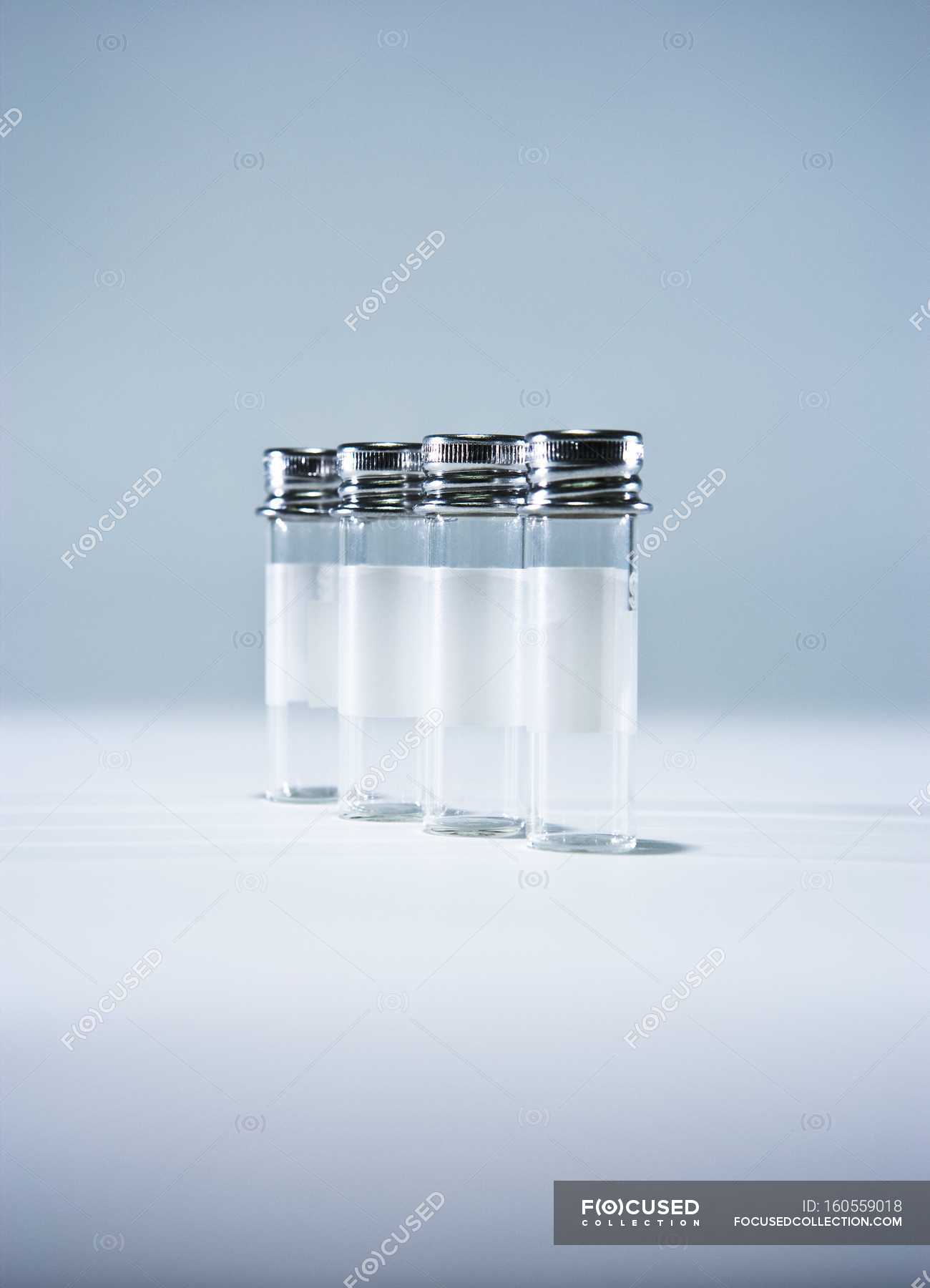 Empty sample bottles with metal lids in a row on table. — Studio Shot
