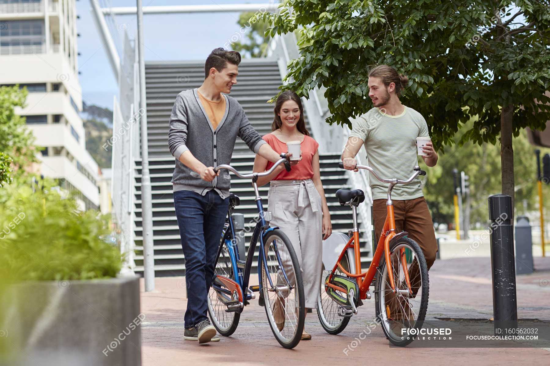 Friends walking with bikes and coffee on street. — Disposable Cup, leisure Stock Photo
