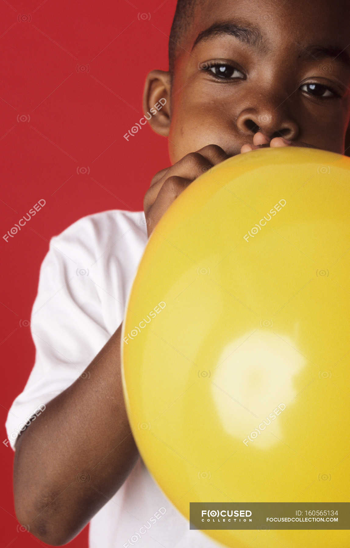 Elementary age boy blowing up yellow balloon. — black, kid - Stock ...