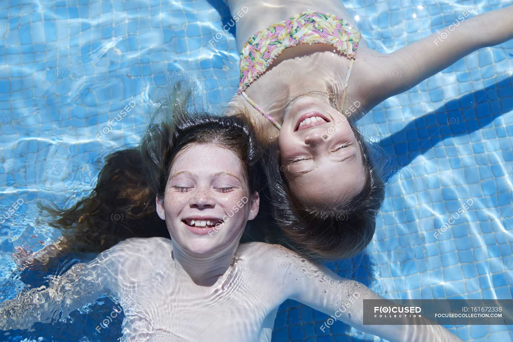 Two Girls Floating In Swimming Pool With Eyes Closed High Angle View — Swimwear Leisure