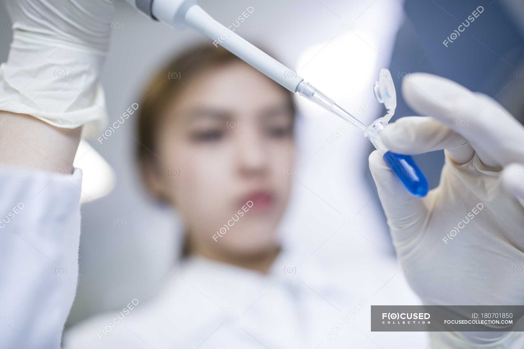 Female lab assistant using pipette, closeup. — blue, biochemical