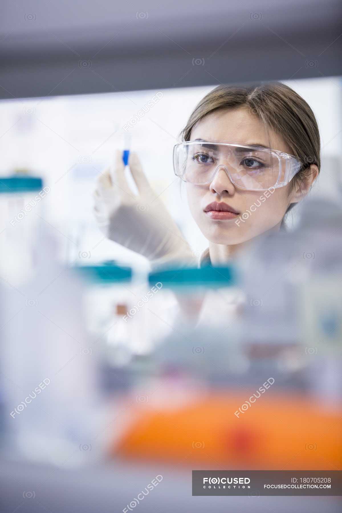 Female laboratory assistant wearing safety goggles. — woman