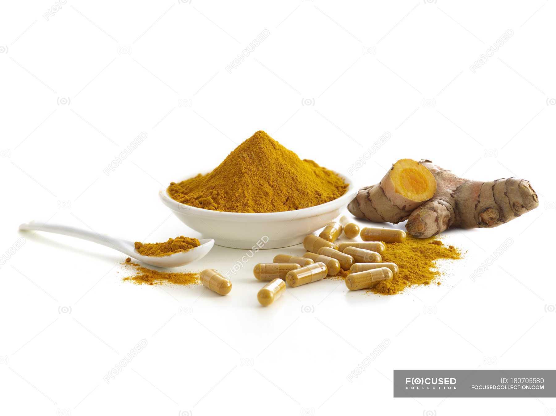 Turmeric root, capsules and dried powder in bowl, studio shot