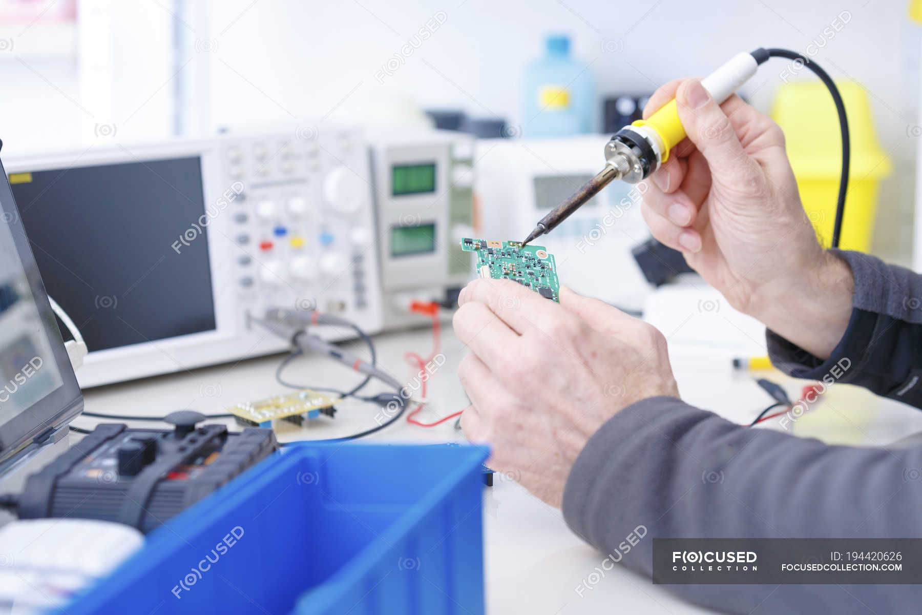 Close-up of technician repairing circuit board in electronics ...