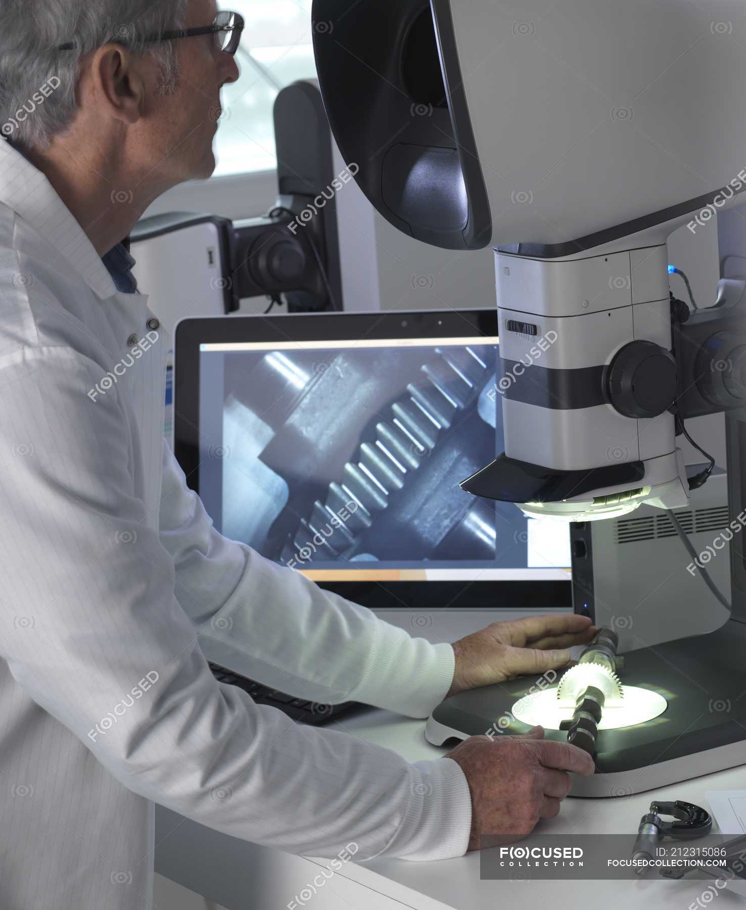 Male engineer using stereo microscope for inspecting manufactured