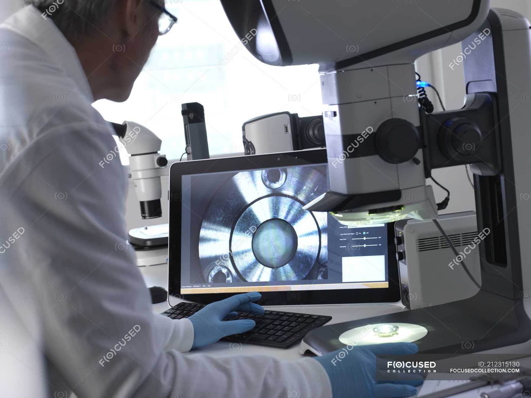Male engineer using stereo microscope for inspecting manufactured