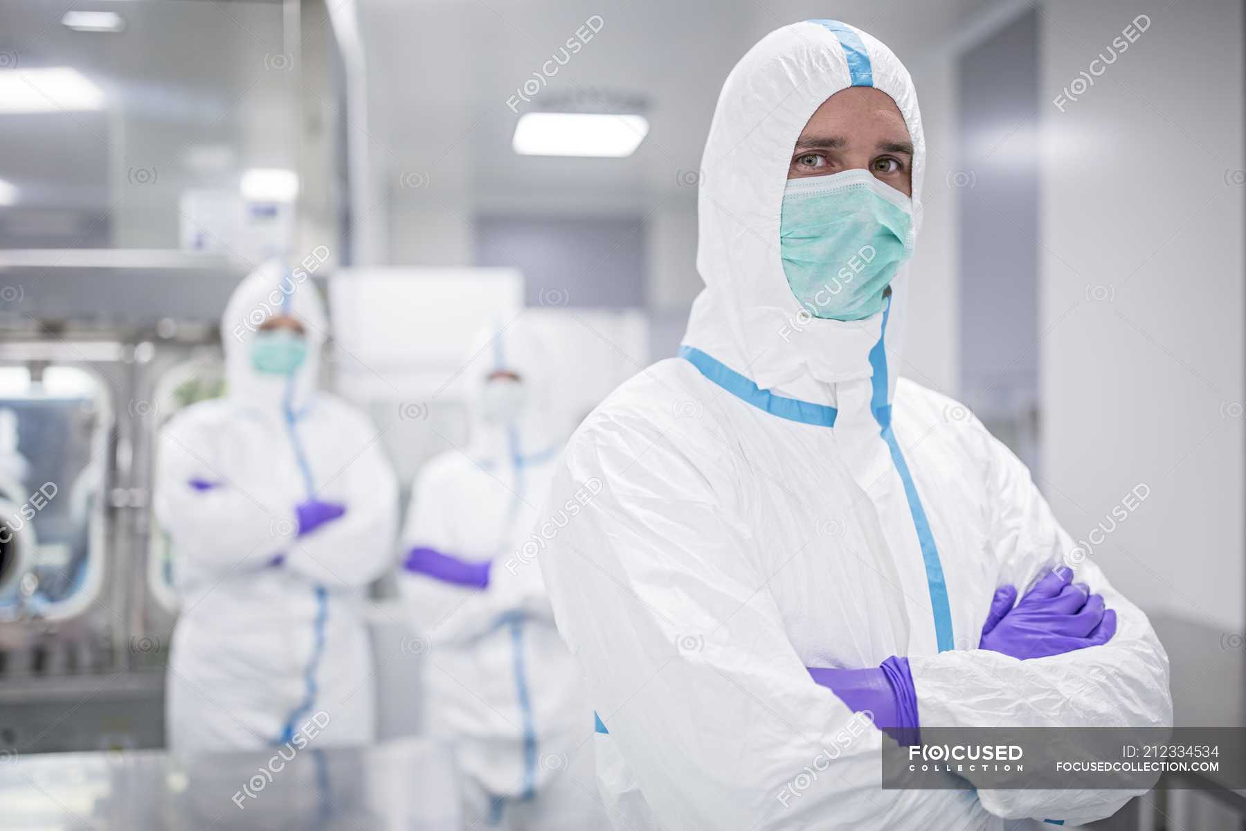 Lab technician in protective clothing with colleagues in sterile