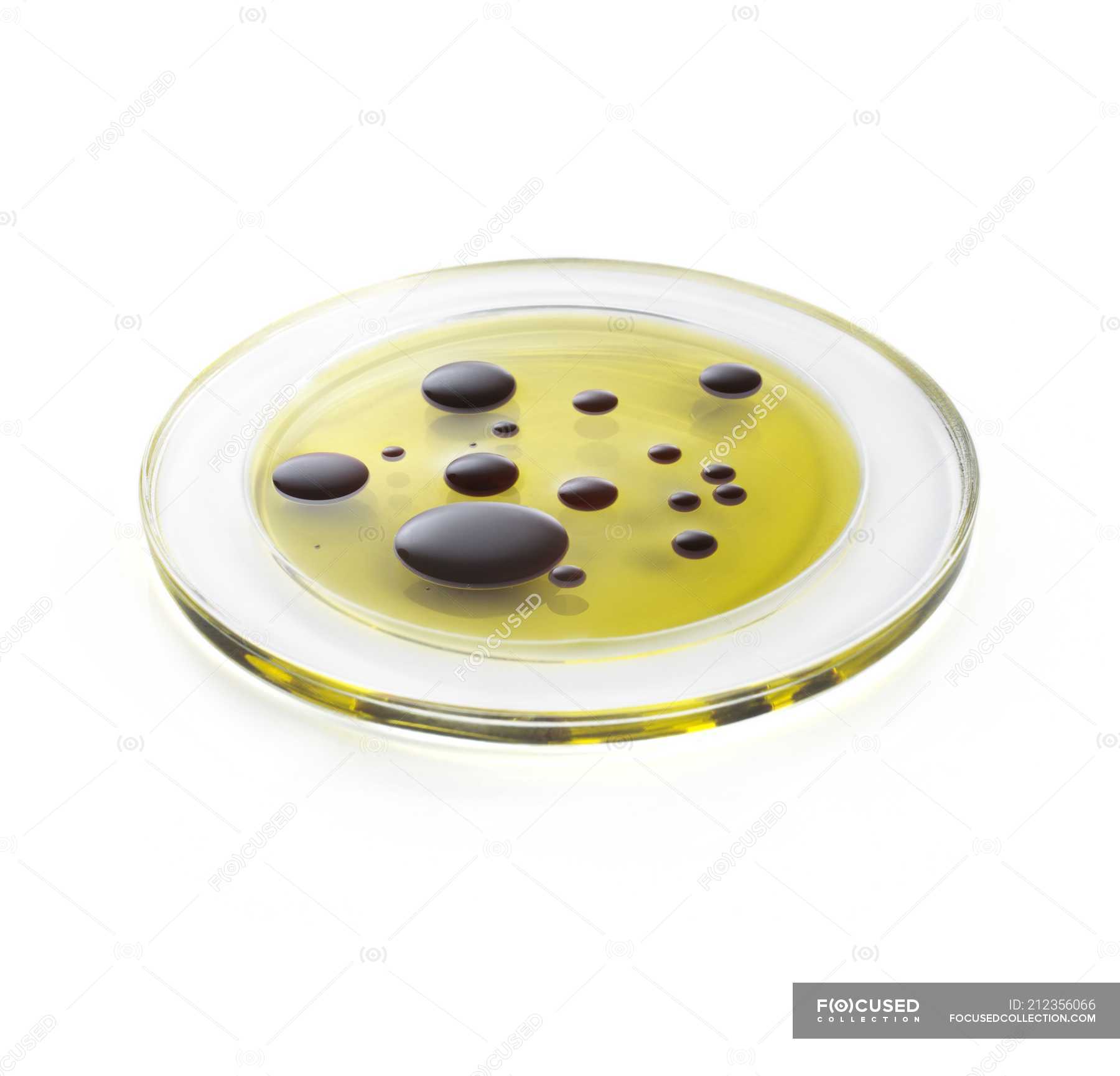 Oil and vinegar on glass plate against white background. — science, immiscible Stock Photo