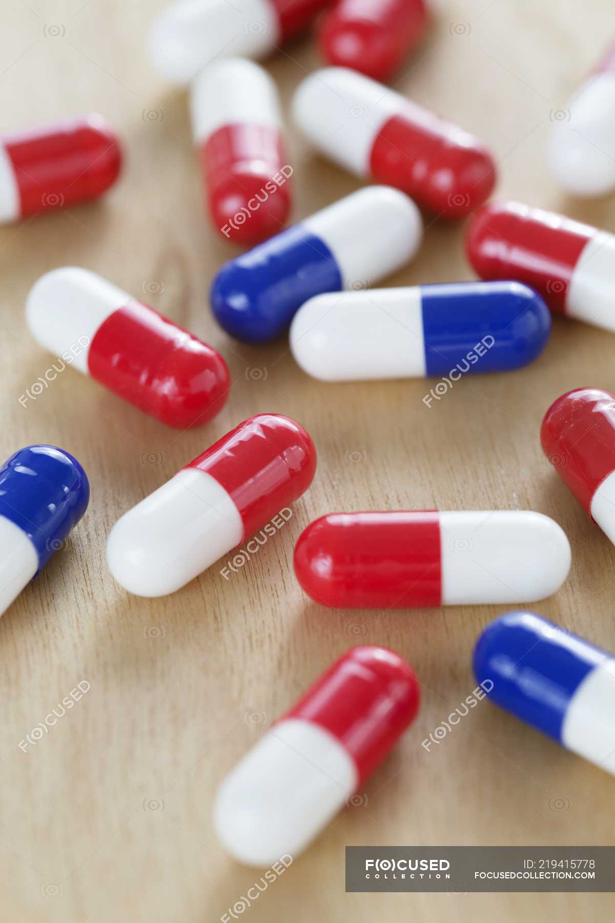 Red and white and blue and white drug capsules on table. — nobody, chemistry Stock Photo | #219415778