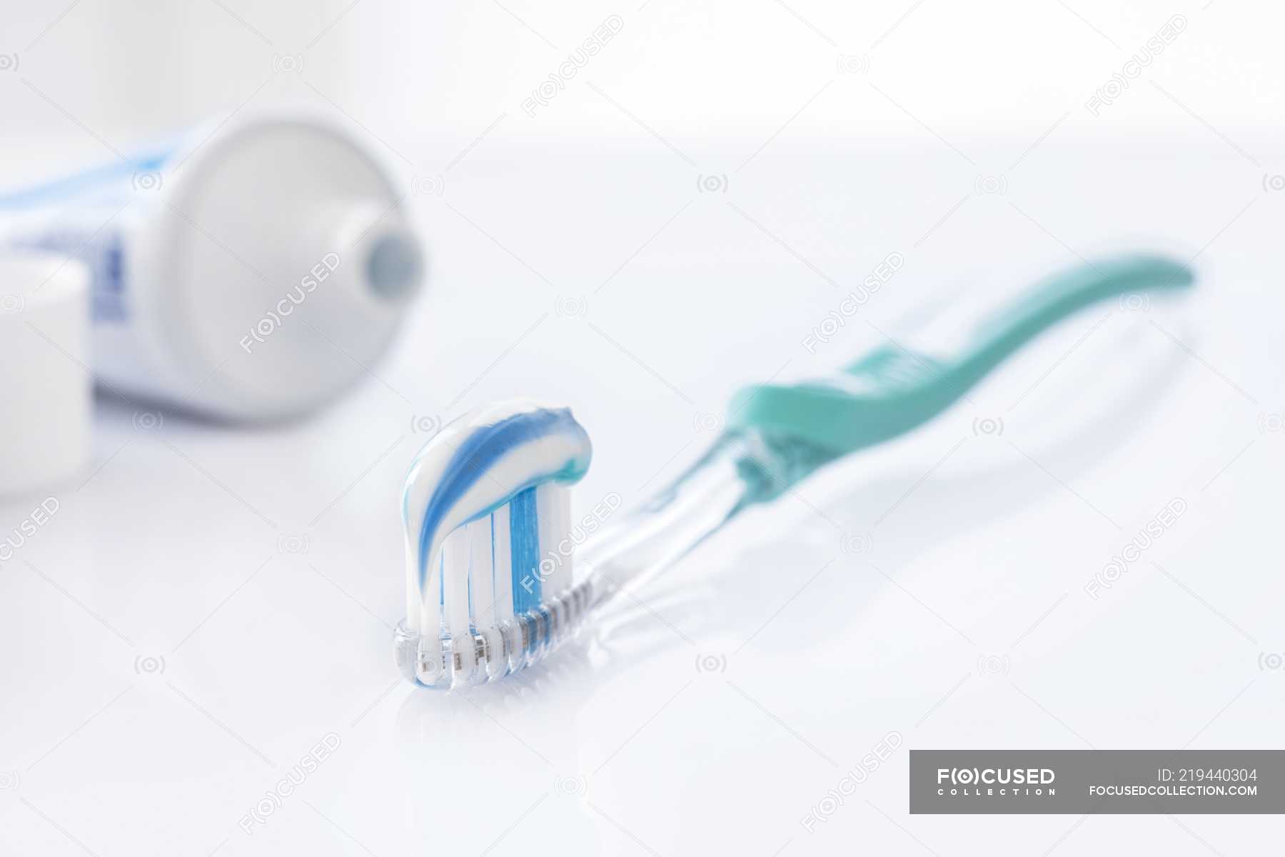 Toothbrush with white and blue toothpaste against white background. — habit, dentistry Stock