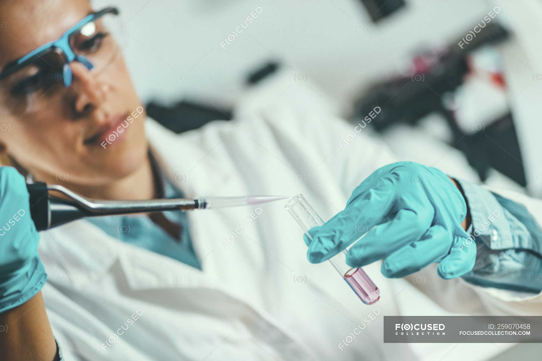Laboratory technician with micro pipette sampling into test tube. — mid