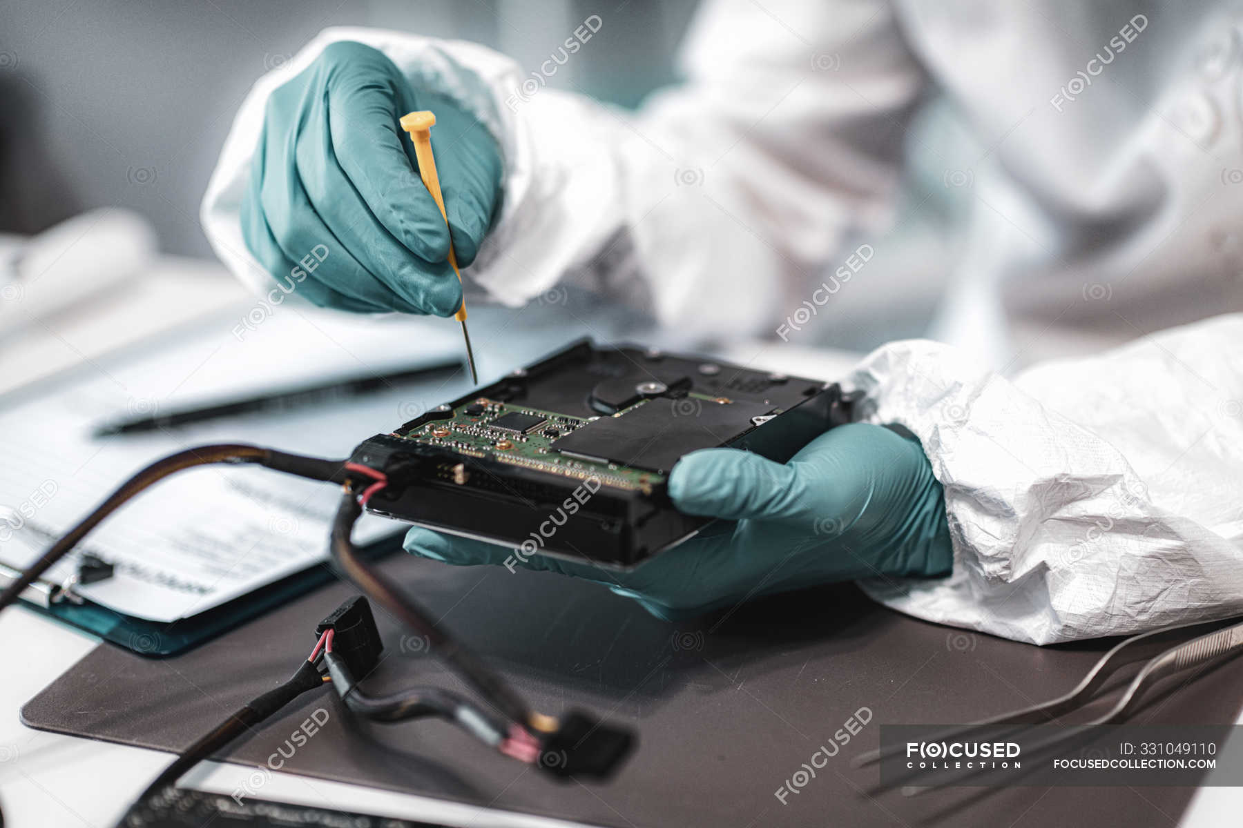 Female digital forensic expert examining computer hard drive in police ...