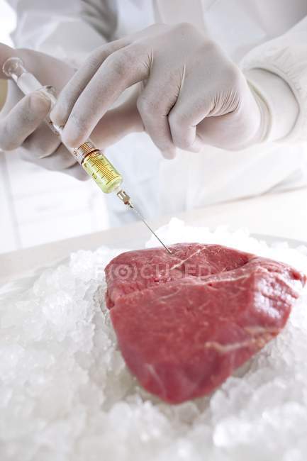 Обрізаний вид вченого, що вводить м'ясо шприцом з жовтою рідиною, концептуальне зображення . — стокове фото