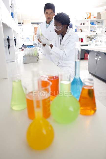 Chimistes travaillant en laboratoire avec verrerie avec des liquides colorés . — Photo de stock