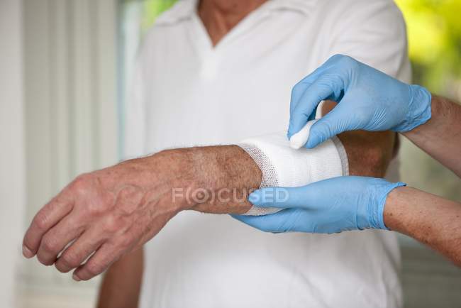 Close-up of male nurse taking care of senior patient wound. — Stock Photo