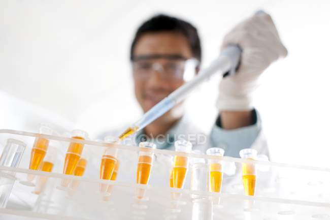 Nahaufnahme eines männlichen Wissenschaftlers, der in Reagenzgläser pipettiert. — Stockfoto