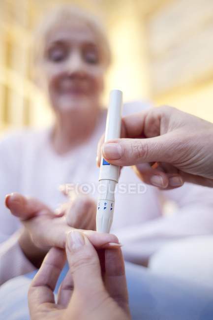 Крупним планом медсестра робить тест на глюкозу крові для старшої жінки . — стокове фото