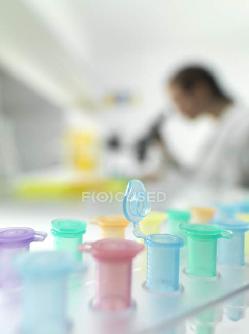 Close-up de tubos de microcentrífuga com biólogo em segundo plano . — Fotografia de Stock