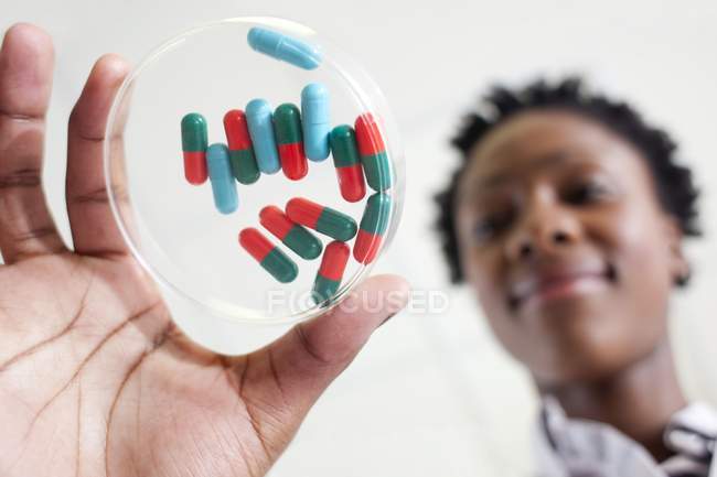 Científica sosteniendo placa petri con pastillas . - foto de stock