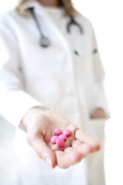 Primer plano de píldoras de color rosa en la mano del médico
. - foto de stock