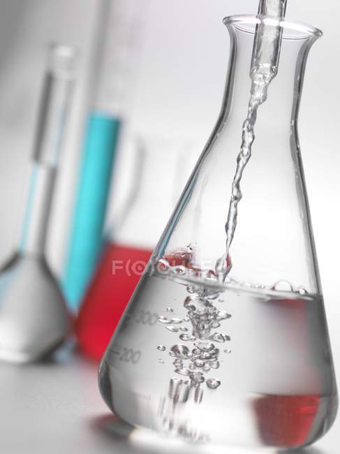 Fluido derramando em copos de laboratório . — Fotografia de Stock