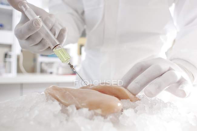 Scientifique injectant de la viande de poulet avec une seringue de liquide blanc, image conceptuelle . — Photo de stock