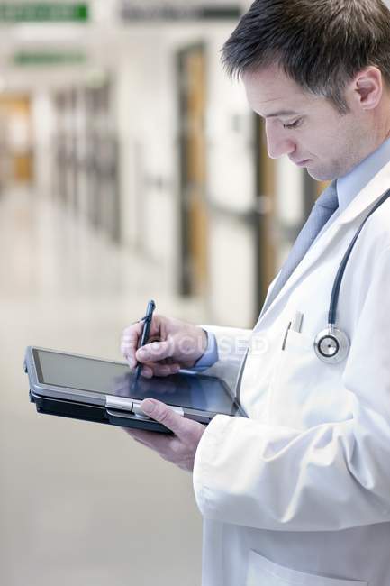 Doctor using digital tablet in clinic hall. — Stock Photo