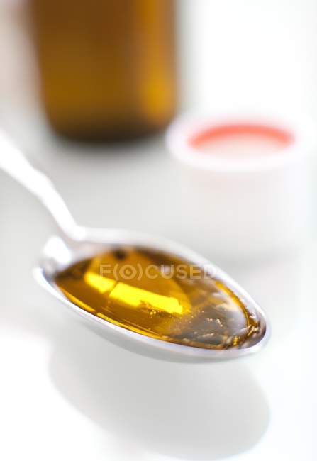 Nahaufnahme von einem Esslöffel gelber Flüssigkeit Medizin. — Stockfoto
