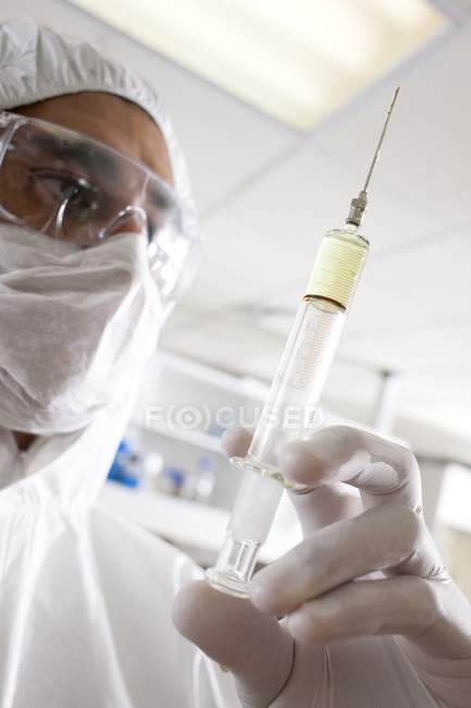 Male scientist in face mask holding syringe. — Stock Photo