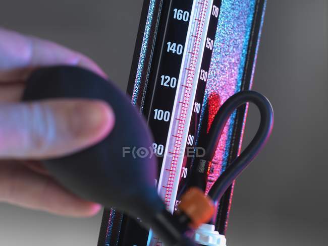 Close-up da mão pessoa empurrando bulbo do medidor de pressão arterial . — Fotografia de Stock