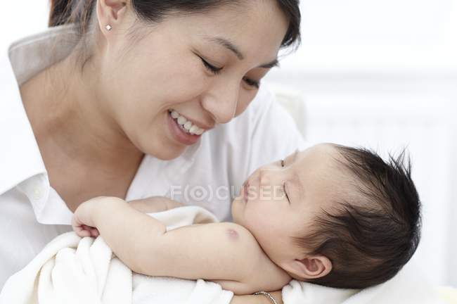 Mutter lächelt und hält schlafendes Baby. — Stockfoto