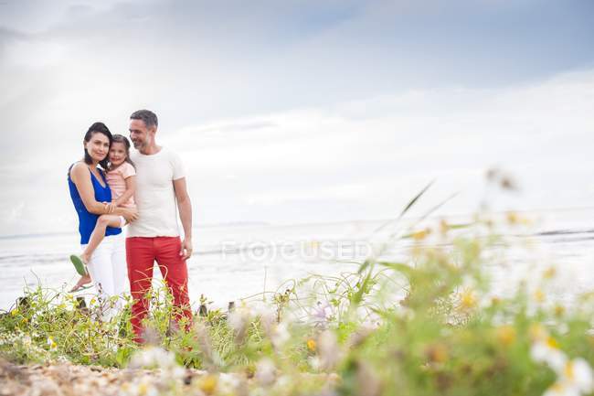 Parents sur le champ côtier avec fille, mère portant fille . — Photo de stock