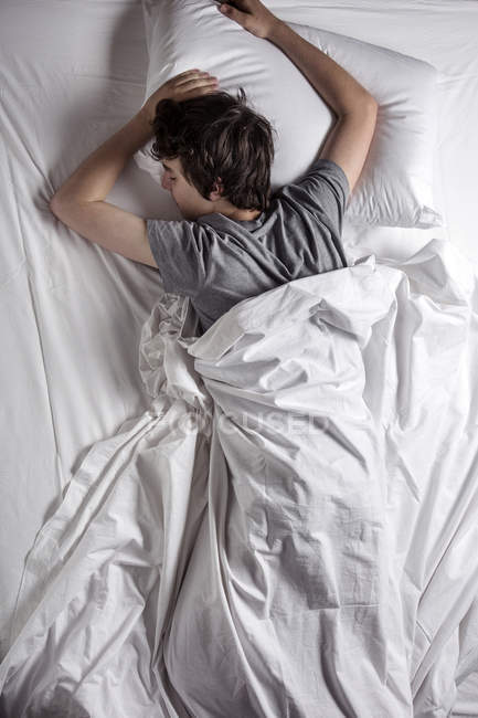 Blick aus der Vogelperspektive auf jungen Mann, der im Bett schläft. — Stockfoto